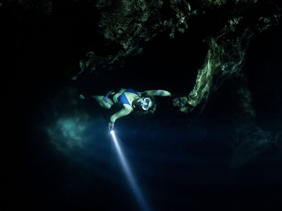 Freediver with a torch in a cavern, Palau